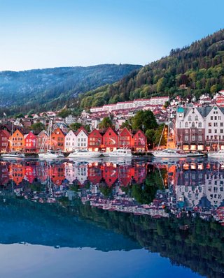A scenic view of colourful buildings along the waterfront reflecting in the calm sea in Bergen, Norway | MSC Cruises
