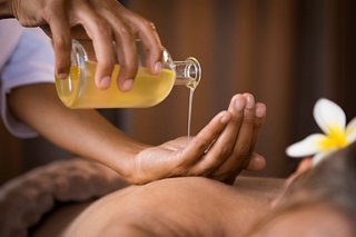 A relaxing massage treatment with oil and a flower, focusing on the back and hands | MSC Cruises