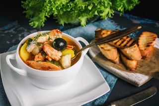 Un cuenco de bouillabaisse lleno de mariscos, servido con pan crujiente | MSC Cruceros
