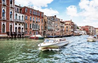 Ein malerischer Blick auf historische Gebäude am Grand Canal in Venedig mit einem Boot, das sanft vorbeischwimmt | MSC Cruises
