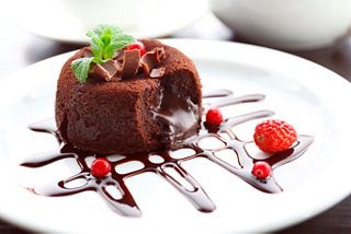 A rich chocolate fondant dessert garnished with fresh berries and mint on a white plate | MSC Cruises