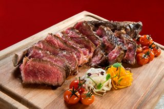 A beautifully presented platter of grilled beef accompanied by vibrant vegetables on a wooden board | MSC Cruises