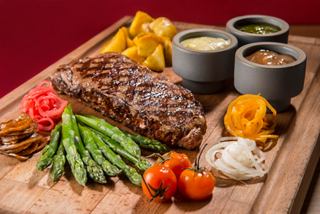 Una bandeja bellamente presentada con un NY sirloin steak, patatas, espárragos y salsas | MSC Cruceros