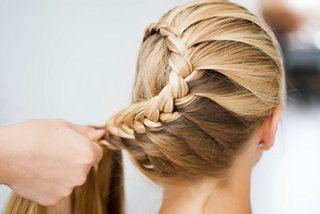A stylist creating a beautiful braided hairstyle for a woman in a serene spa environment | MSC Cruises