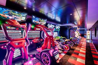A vibrant virtual games arcade featuring modern gaming stations and colourful lighting on MSC Grandiosa | MSC Cruises