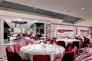 Elegante comedor con mesas redondas y decoración vibrante, invitando a los huéspedes a disfrutar de una comida memorable | MSC Cruceros