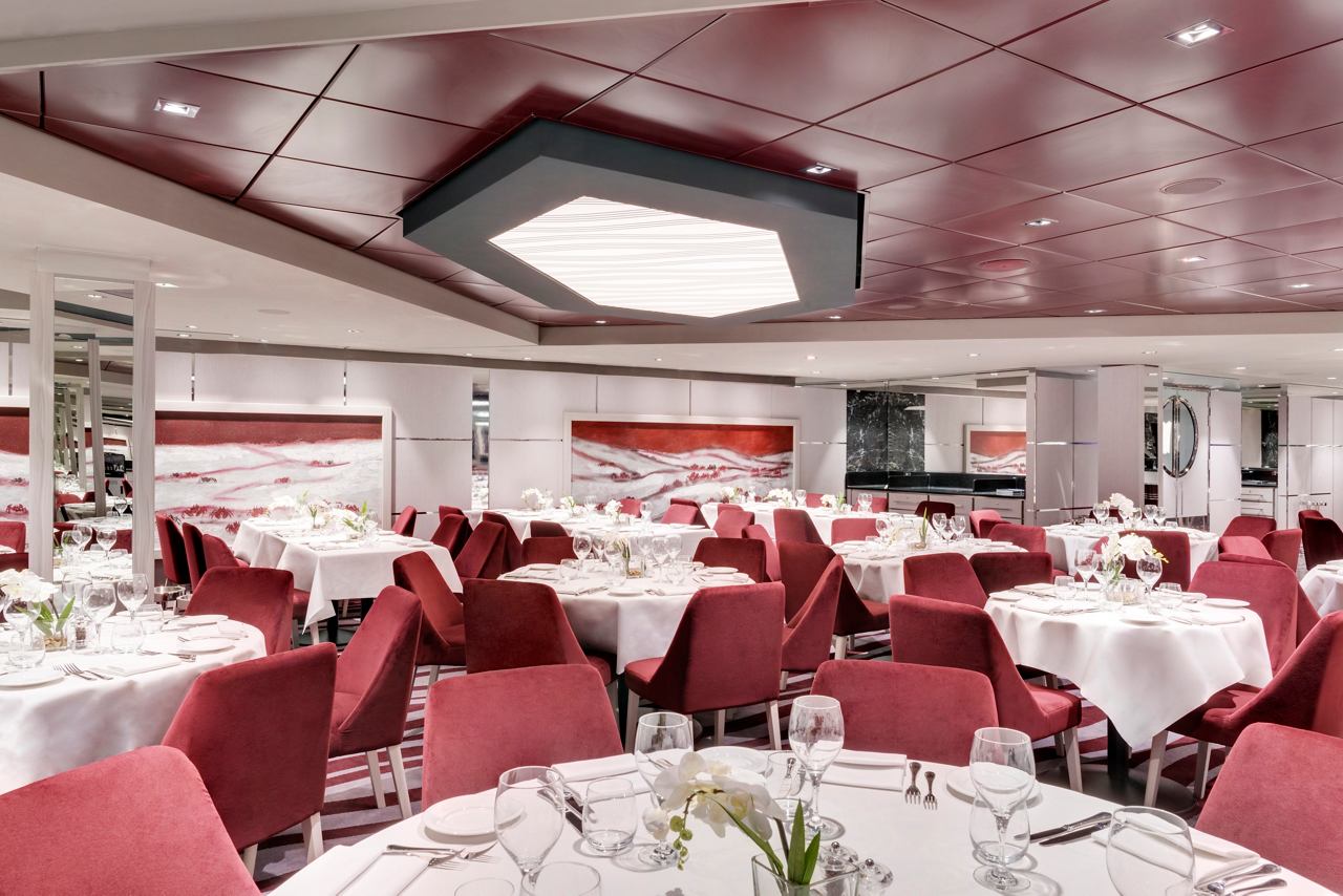 Elegant dining setup in the main restaurant of MSC Grandiosa, featuring red and white decor for a welcoming atmosphere | MSC Cruises