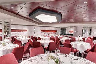 Configuración de cena elegante en el restaurante principal de MSC Grandiosa, con decoración roja y blanca para un ambiente acogedor | MSC Cruceros