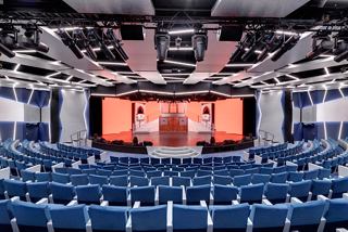 A spacious theatre with blue seating and a large stage, ready for entertainment and performances on MSC Grandiosa | MSC Cruises