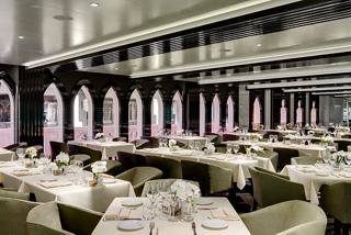 Elegant dining tables set in the main restaurant, featuring large windows for natural light | MSC Cruises