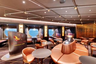 A welcoming lounge area featuring tables and porthole views at Jean-Philippe Chocolat & Café on MSC Grandiosa | MSC Cruises