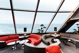 A stylish lounge area with comfortable seating and panoramic windows overlooking the sea | MSC Cruises