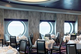 A spacious dining area with elegant tables and porthole windows, inviting guests to enjoy their meals | MSC Cruises
