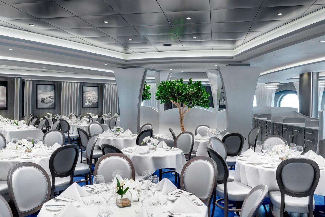 Elegant dining area in the main restaurant, featuring beautifully set tables and lush greenery | MSC Cruises
