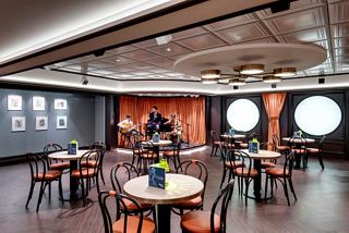 A vibrant restaurant setting with tables arranged for guests to enjoy live music and art experiences | MSC Cruises