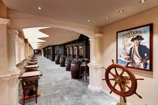 A welcoming corridor leading to the Masters of the Sea pub, featuring elegant decor and a ship's helm | MSC Cruises