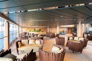 Inviting seating area in the Safari Bar, showcasing large windows with sea views and warm ambience | MSC Cruises