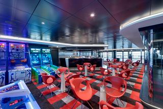 A vibrant sports bar with red seating and game areas, inviting guests to relax and enjoy | MSC Cruises