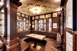 A warm and inviting pub area with elegant wood decor, a table, and seating for relaxation and socialising | MSC Cruises