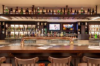 The bar counter of the Masters of the Sea lounge, featuring drinks and monitors in a welcoming setting | MSC Cruises