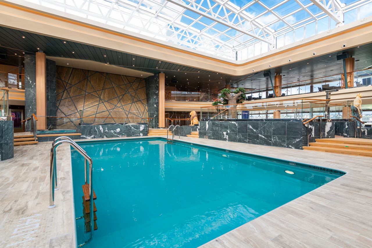 A serene indoor pool area with a sliding roof, surrounded by elegant wooden features and ample seating | MSC Cruises