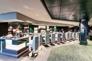 A vibrant cocktail bar with guests enjoying drinks at the counter and spacious seating areas for relaxation | MSC Cruises