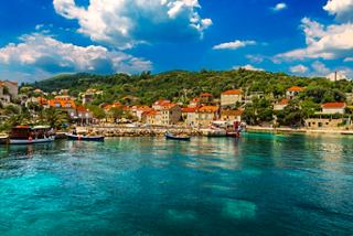 A picturesque view of colourful buildings by the sea in Sipano, Croatia, surrounded by lush hills and clear waters | MSC Cruises