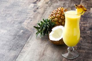 A refreshing Piña Colada garnished with fruit, served in a glass on a wooden surface | MSC Cruises