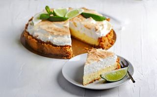 A delicious key lime pie garnished with lime slices and mint on a wooden platter, alongside a slice on a plate | MSC Cruises