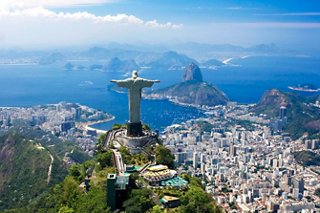 Aerial view of Christ the Redeemer statue overlooking Rio de Janeiro, surrounded by lush vegetation and scenic coastline | MSC Cruises