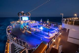 A vibrant evening scene of the MSC Seaview deck featuring the Panorama Pool and illuminated areas | MSC Cruises