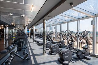 A bright and spacious gym area with modern fitness equipment and large windows overlooking the sea | MSC Cruises