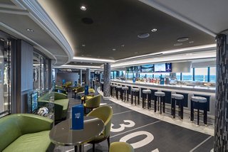 A stylish sports bar featuring comfortable seating, a bar counter, and large windows with sea views | MSC Cruises