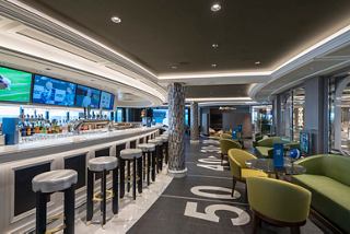 Un vivace ambiente di sport bar con posti a sedere, tavoli e un bancone, con monitor per l'intrattenimento | MSC Crociere