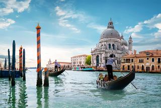 Gondolas glide through the canals of Venice, with the iconic basilica in the backdrop under a bright sky | MSC Cruises