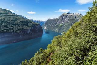 Una vista impresionante del fiordo de Geiranger con montañas y exuberante vegetación a lo largo de la orilla | MSC Cruceros