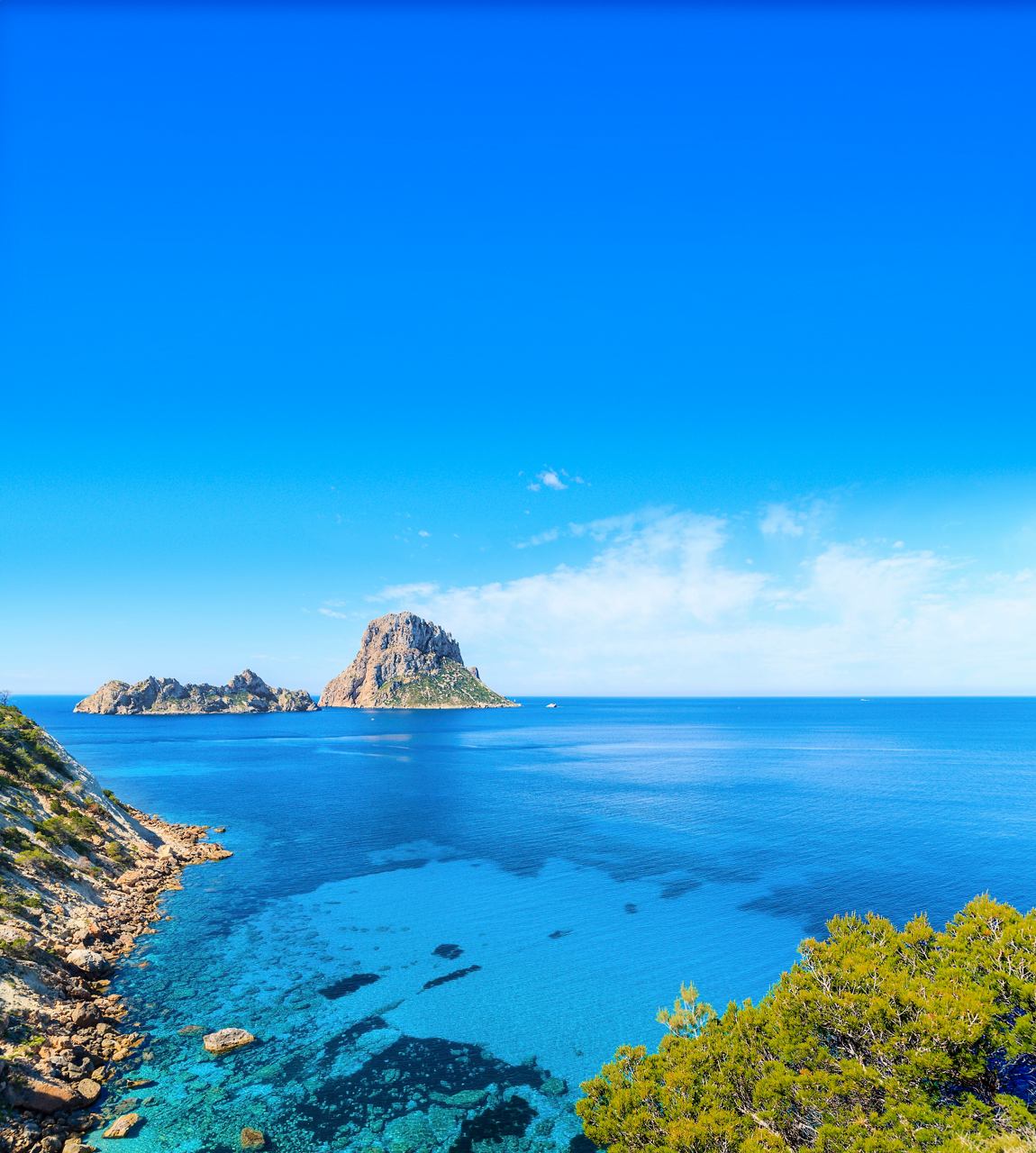 A stunning panoramic view of Cala D'Hort in Ibiza, showcasing the tranquil Mediterranean sea and clear blue skies | MSC Cruises