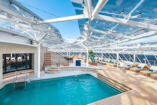 A luxurious pool area in the MSC Yacht Club featuring sunbeds, towels, and a stunning sea view | MSC Cruises