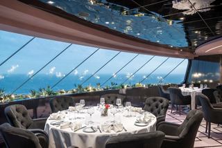 A luxurious dining area with elegant tables and stunning sea views through large glass windows | MSC Cruises