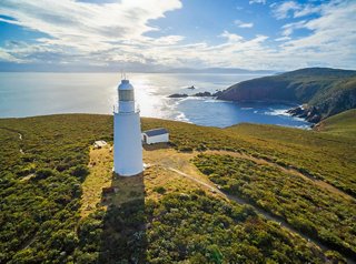 A scenic view of a lighthouse on Bruny Island, overlooking the coastline and sea during sunset | MSC Cruises