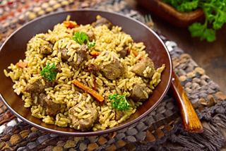 A vibrant bowl of Khuzi, a traditional Emirati dish with spiced rice, lamb, and carrots, garnished with fresh herbs | MSC Cruises