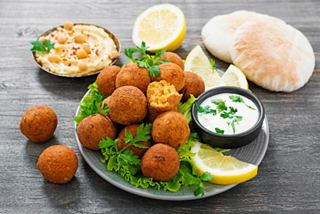 A vibrant plate featuring falafel, pita bread, hummus, and fresh lemon slices, celebrating Bahraini cuisine | MSC Cruises