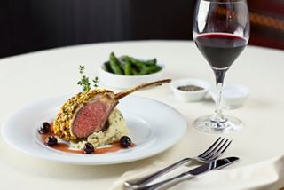 A beautifully plated lamb dish accompanied by wine and greens, inviting a delightful dining experience | MSC Cruises