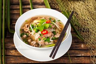 Un tazón humeante de pho con fideos, carne de res, menta y hierbas frescas, servido con palillos | MSC Cruceros