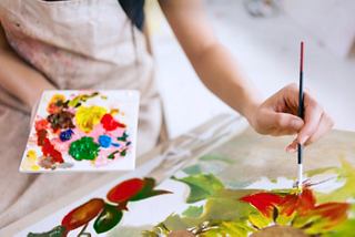 Una mano sostiene un pincel sobre una paleta colorida durante un taller creativo | MSC Cruceros