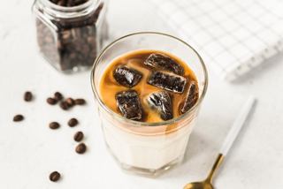 A creamy coffee dessert topped with coffee beans, served with a spoon beside scattered coffee beans | MSC Cruises
