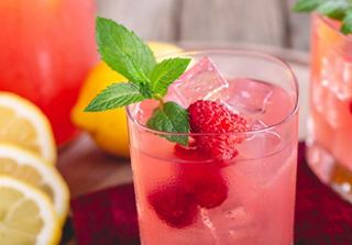 A refreshing cocktail garnished with mint leaves and raspberries, served over ice with citrus slices | MSC Cruises