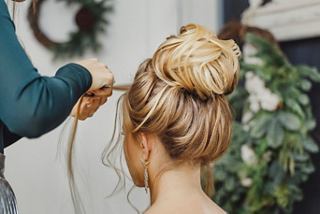 A hairstylist creates an elegant updo for a blonde woman, highlighting the artistry of hair design | MSC Cruises