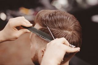 A barber carefully styles a man's hair using scissors and a comb at MSC Aurea Spa | MSC Cruises