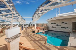 A serene view of the MSC Yacht Club pool area, inviting relaxation under a clear blue sky | MSC Cruises